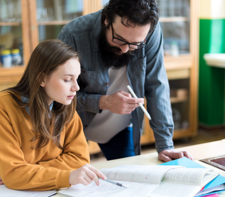 Young teacher helping his student in chemistry class. Education, Tutoring and Encouragement concept. Reading should be a right, not a privilege