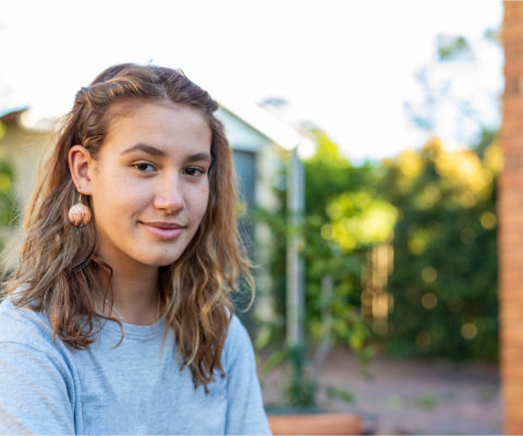 A young woman smiling outdoors.