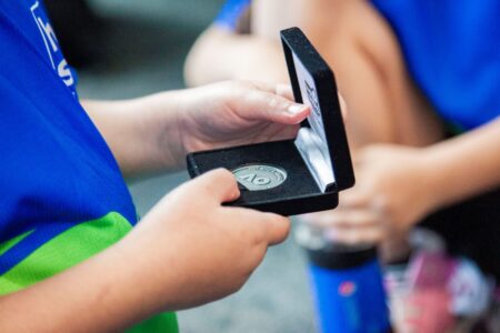 A child's hands hold a box containing the Australian Open 2024 commemorative coin.