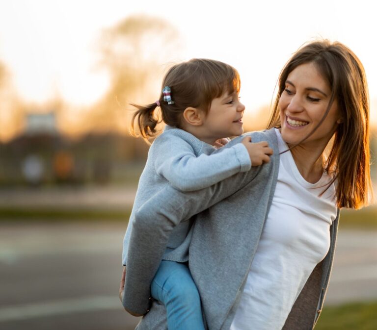 A smiling woman carrying a young girl on her back
