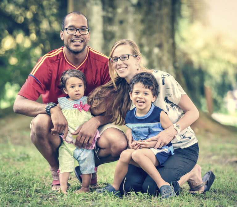 A family with two children smiling at a park